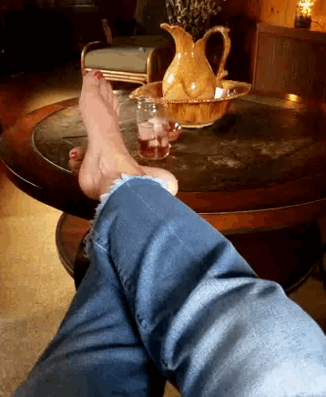 a woman 's feet are resting on a table next to a pitcher