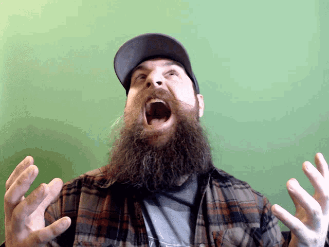 a man with a beard wearing a plaid shirt is screaming with his mouth open