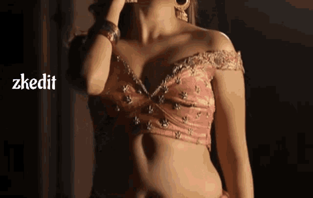 a woman in a pink crop top is standing in the dark .