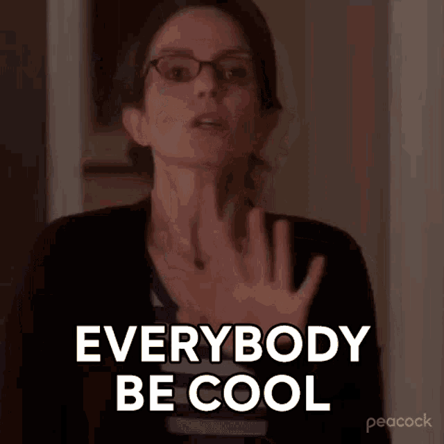 a woman wearing glasses is saying `` everybody be cool '' while standing in front of a door .