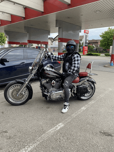 a man on a harley davidson motorcycle in front of a gas station