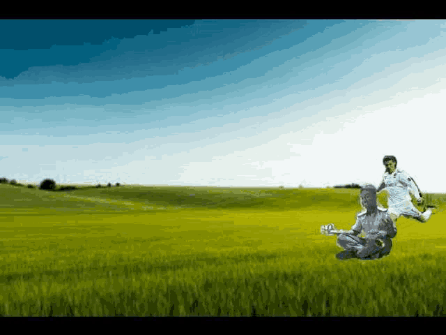 a man in a white shirt is kicking a soccer ball while another man sits on the grass