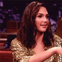 a woman in a gold sequined top is sitting in a chair .