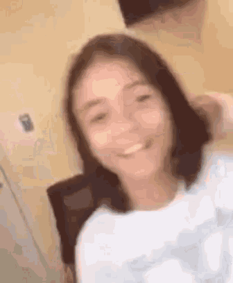 a young girl is taking a selfie in a room and smiling at the camera .