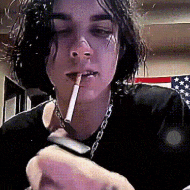 a man is smoking a cigarette in front of an american flag