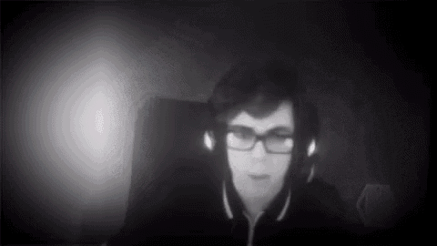 a young man wearing glasses and headphones is sitting in a dark room .