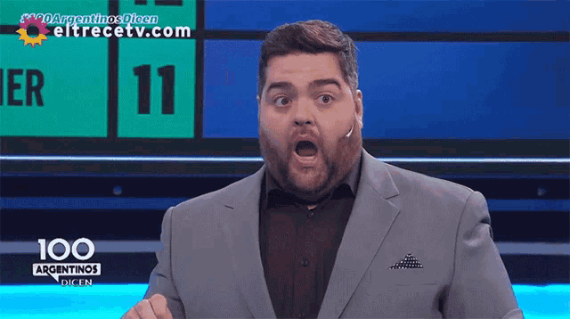 a man in a suit stands in front of a sign that says 11 on it