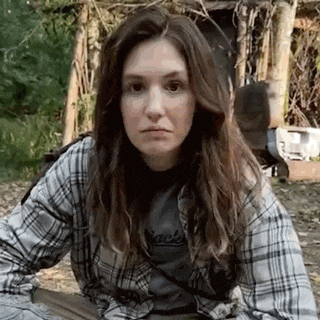 a woman in a plaid shirt is sitting on the ground in front of a building .