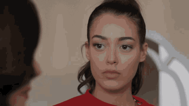 a woman in a red sweater is looking at herself in a mirror