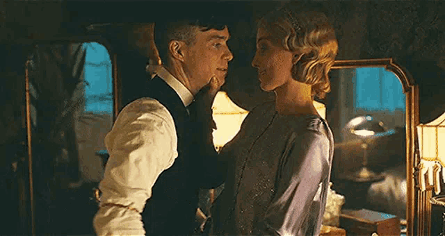 a man and woman are kissing in a room in front of a mirror .