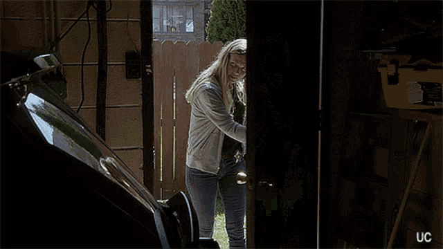 a woman is holding a gun in a garage with uc written on the bottom