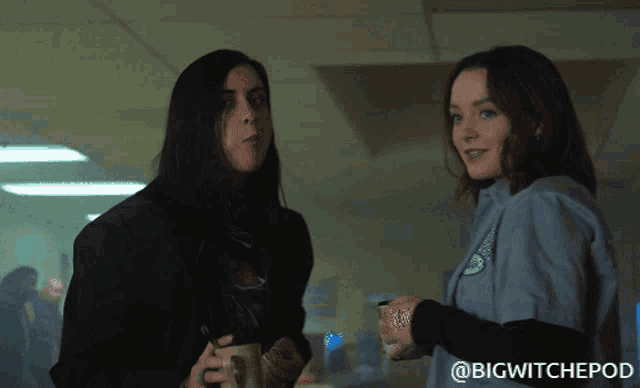two women standing next to each other with a big witchepod logo behind them