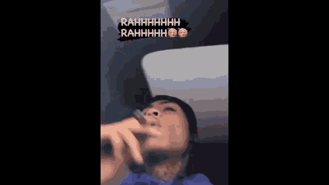 a man in a blue shirt is making a funny face while holding a cell phone .