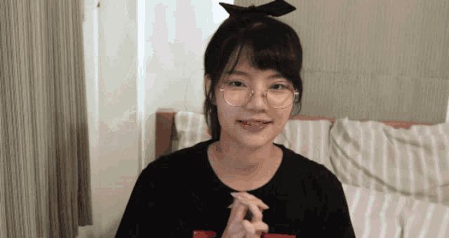 a girl with glasses and a bow in her hair is smiling
