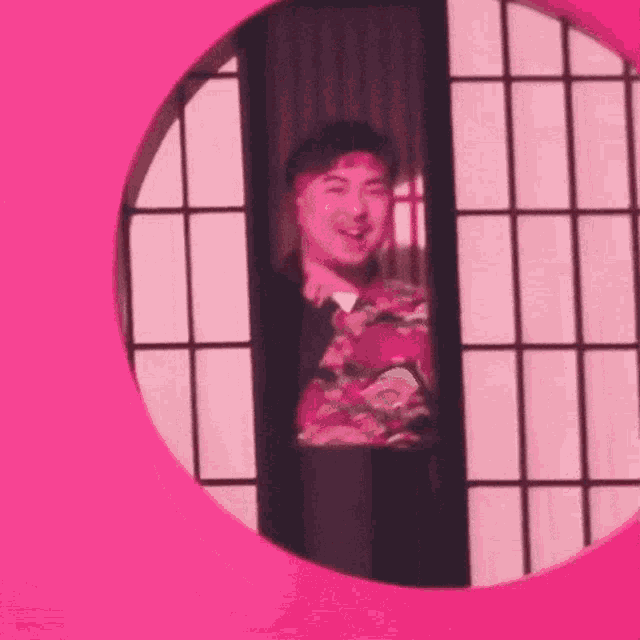 a man is standing in a pink circle in front of a pink wall .