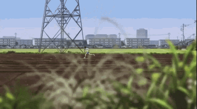 a person is running in a field with a tower in the background