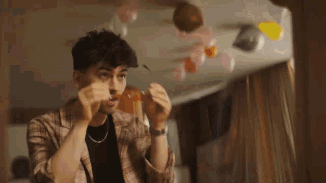 a man in a plaid shirt is blowing up balloons in a room