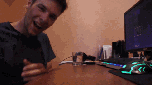 a man is laughing in front of a computer monitor and keyboard