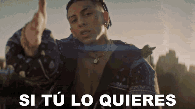 a man in a bandana jacket is pointing at the camera with the words si tu lo quieres above him
