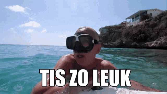 a man wearing a mask and goggles is swimming in the ocean with the words tis zo leuk above him