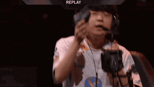 a man wearing headphones and a red bull shirt drinks from a bottle