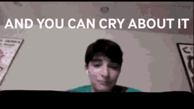 a man is sitting in front of a computer screen with the words `` and you can cry about it '' written above him .