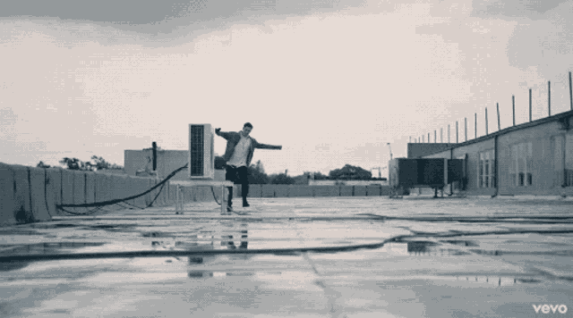 a black and white photo of a man on a roof with the words vevo on the bottom right