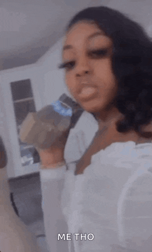 a woman in a white dress is holding a bottle of soda in her hand .