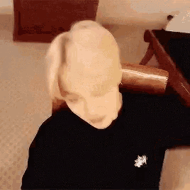a man with blonde hair is sitting in a chair in a bedroom .