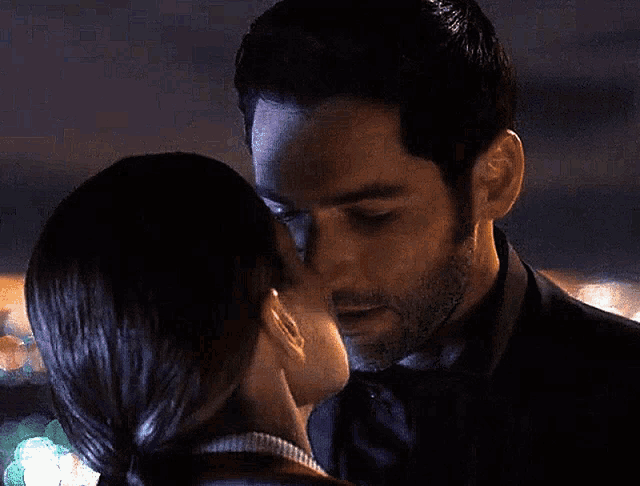 a woman kissing a man on the cheek in a dark room