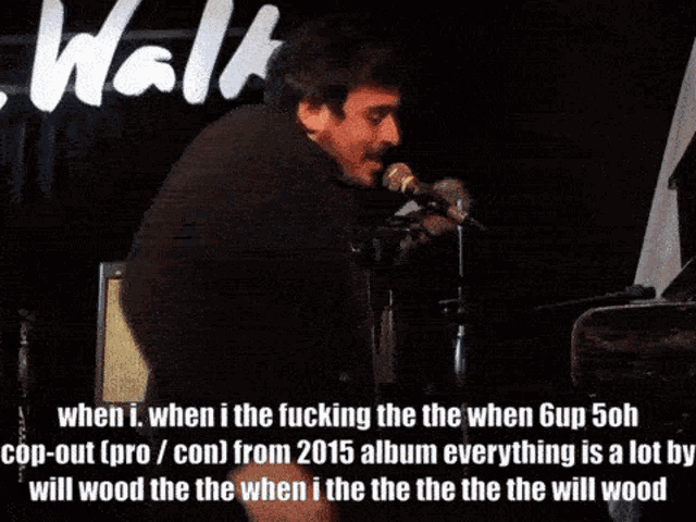 a man singing into a microphone while playing a piano in front of a sign that says walk