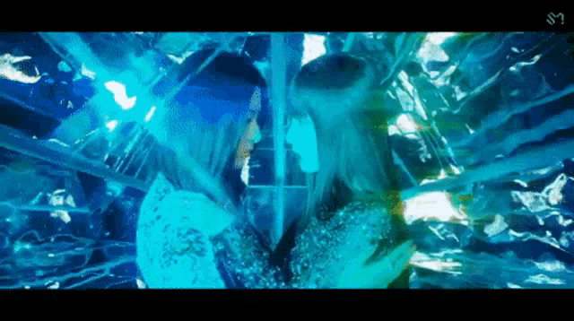 a woman with blue hair is standing next to another woman in a room with a mirror .