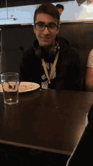 a man wearing glasses and headphones has a lanyard around his neck