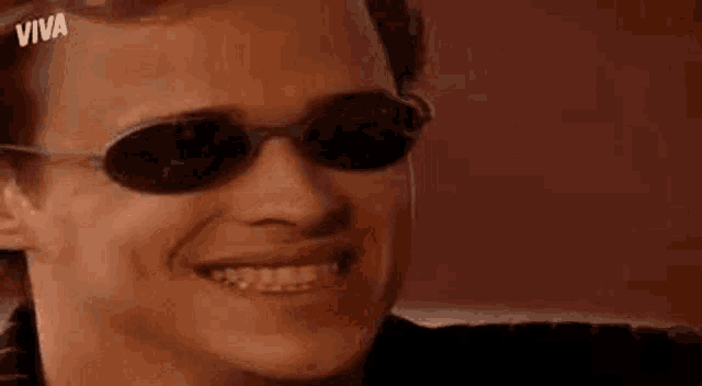a man wearing sunglasses is smiling for the camera .