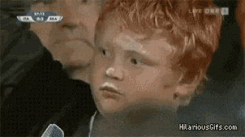 a young boy with red hair looks at the camera while a man looks on ..