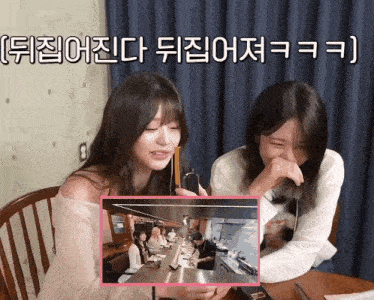 two girls are sitting at a table with a picture of a restaurant behind them