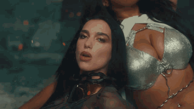 a woman in a silver bra sits next to another woman in a white top