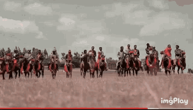 a group of people are riding horses in a field with imgplay in the corner