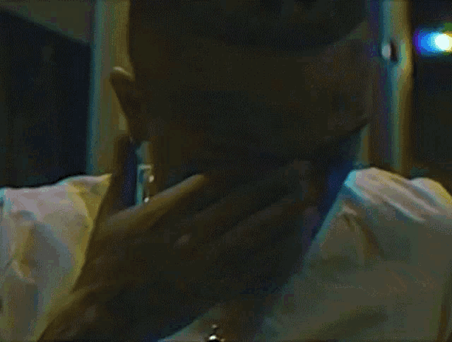 a man is talking on a cell phone in a dark room while wearing sunglasses .