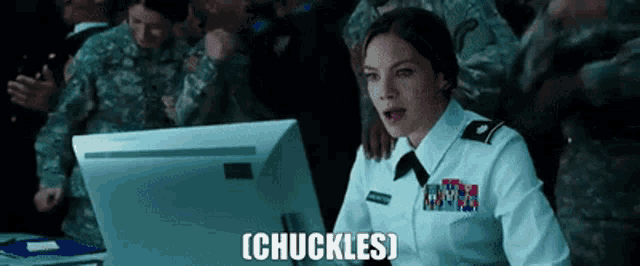 a woman in a military uniform is sitting at a desk in front of a computer .