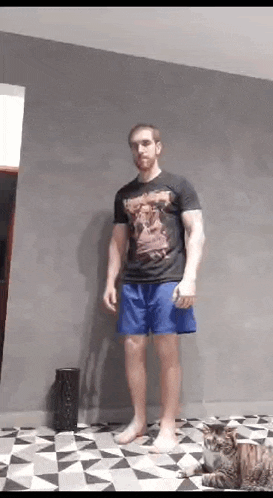 a man in shorts is standing next to a cat on a checkered floor .