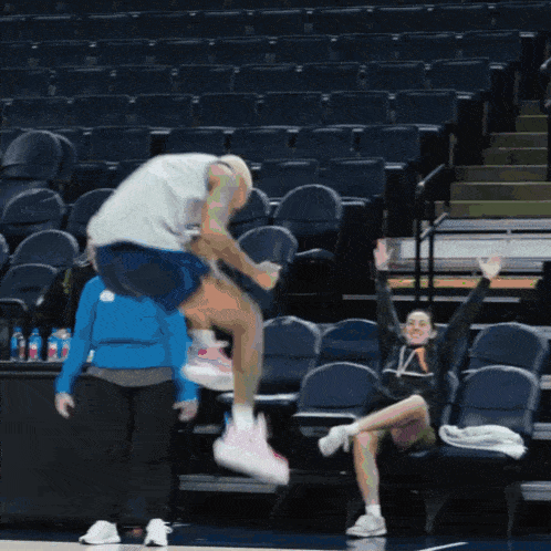 a basketball player is jumping in the air while a woman watches