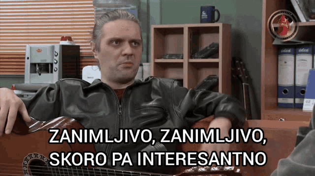 a man in a leather jacket is playing a guitar and says " zanimivo "