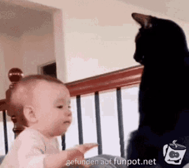 a baby is playing with a black cat on the stairs .