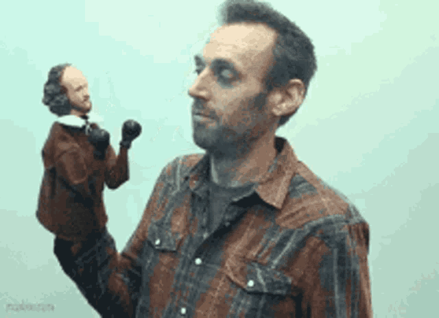 a man in a plaid shirt is holding a small puppet