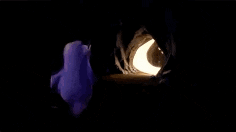 a purple monster is standing in a dark cave with a light coming out of it
