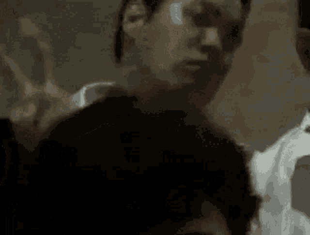 a blurry picture of a man standing next to another man in a room .