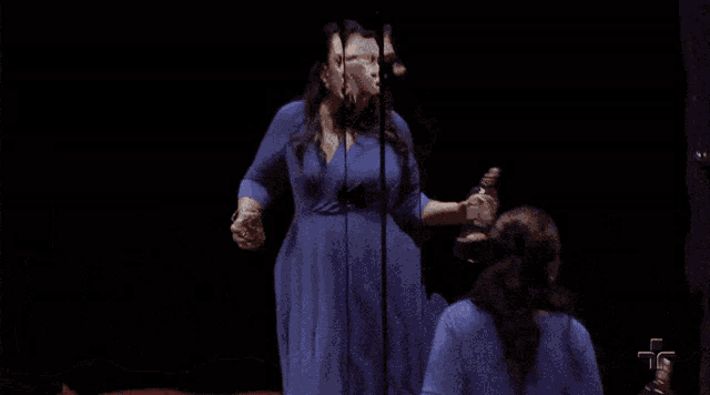 a woman in a blue dress is holding a bottle of wine in front of a man in a suit