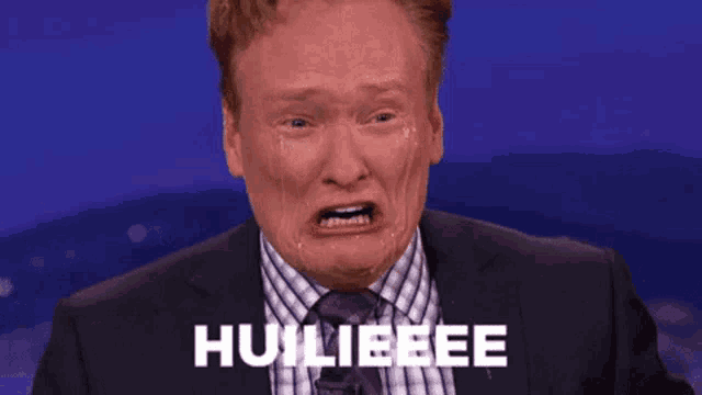 a man in a suit and tie is making a funny face and crying with the word huileeee written on the screen