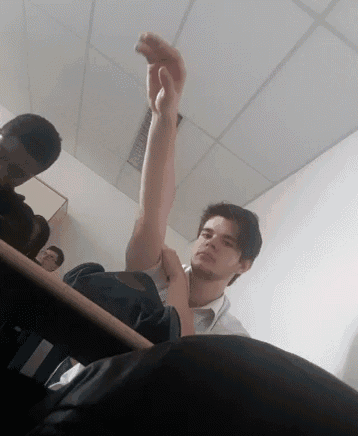 a man is sitting at a desk with his arm up in the air